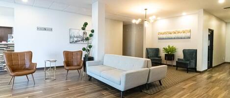 Un vestíbulo moderno con un sofá de gris claro, dos sillones de cuero marrón y una mesita.