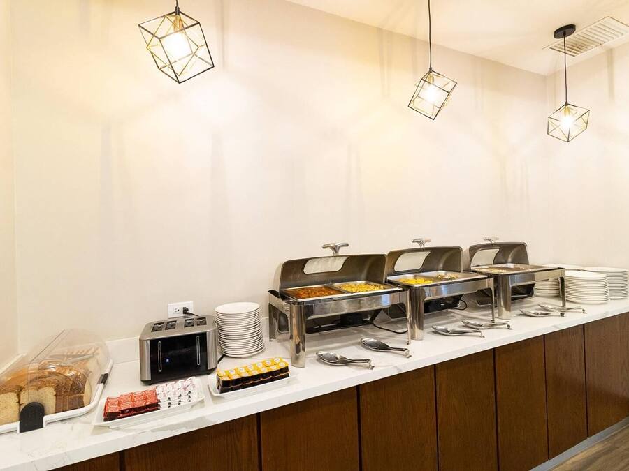 A buffet setup with various food items and utensils, including a toaster and a bread dispenser.