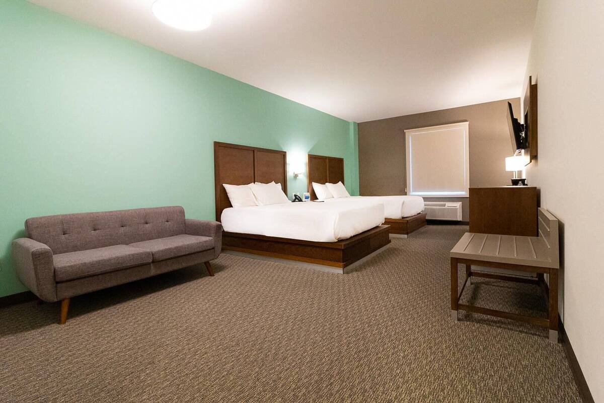 A hotel room with a bed, a sofa, a desk, and a lamp.