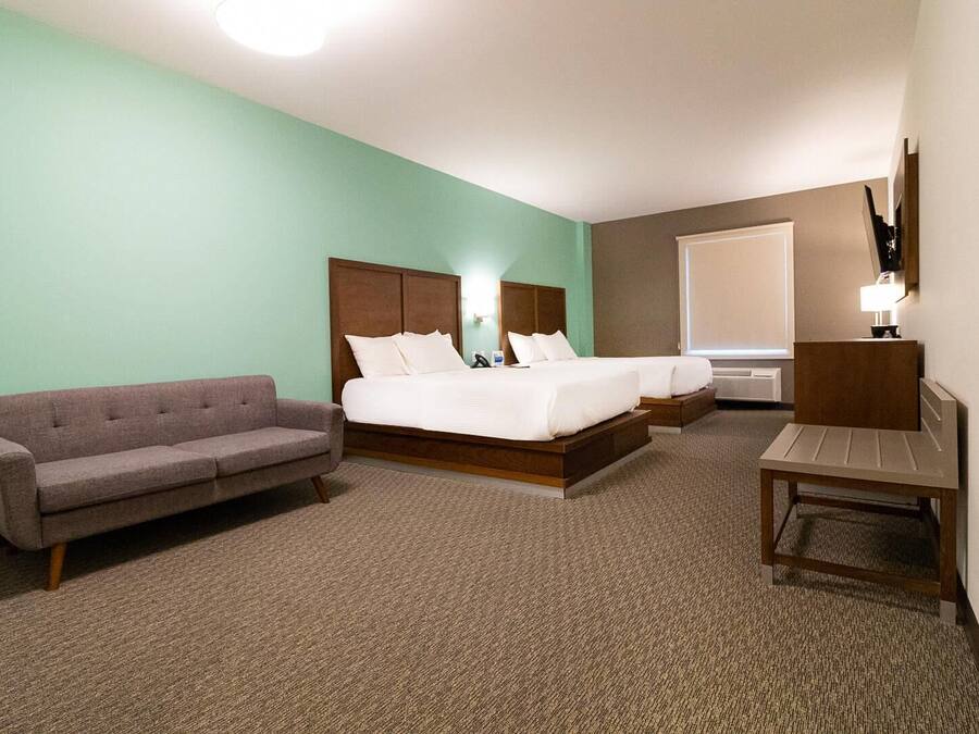 A hotel room with a bed, a sofa, a desk, and a lamp.