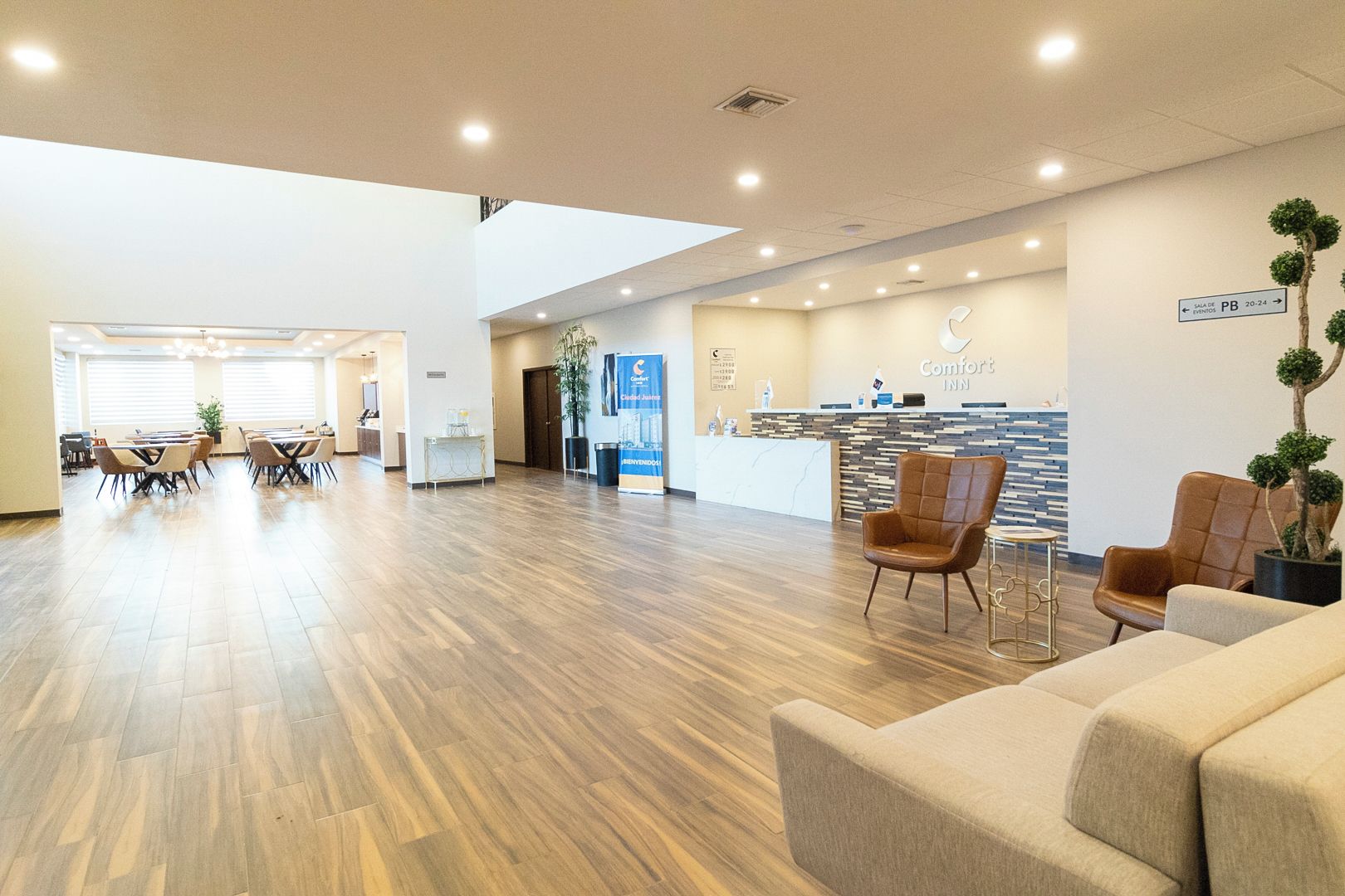 A hotel lobby with a reception desk, seating area, and a dining space.