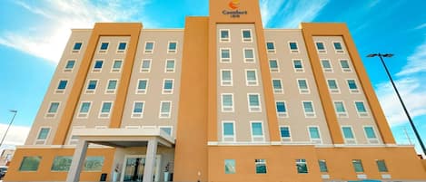 A multi-story hotel with a central entrance, large windows, and a prominent Comfort Inn logo.