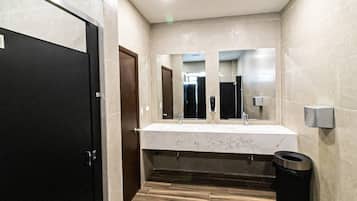 Un baño moderno con lavamanos de mármol, un espejo grande y suelo de madera.