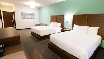 A hotel room with two beds, a desk, a chair, and a small table.