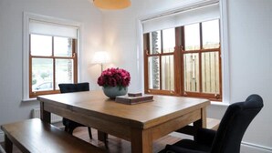 A dining area with a wooden table, chairs, a vase of flowers, and a pendant light. - Number Two Dingle: Large Family Holiday Home (Dingle)