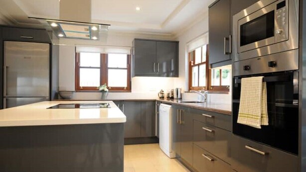 A modern kitchen with stainless steel appliances, a large island, and a view of the outdoors through the windows. - Number Two Dingle: Large Family Holiday Home (Dingle)