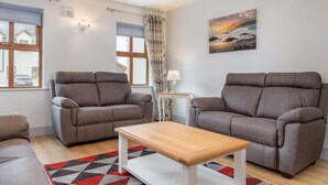 Un salon avec deux canapés gris, une table basse en bois et un tapis à motifs.