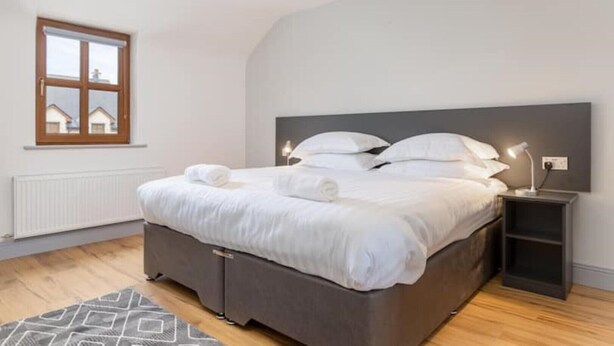 Une chambre à coucher avec un lit, des tables de chevet, une fenêtre et un radiateur.
