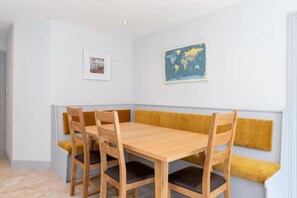 Ein Essbereich mit Holztisch und Stühlen, einer Sitzbank an der Wand und zwei gerahmten Bildern.