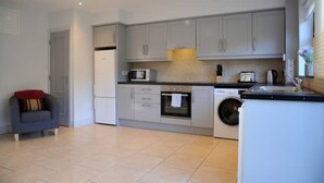 Una cucina compatta con mobili grigi, un forno a microonde, un forno, una lavatrice e un lavello.