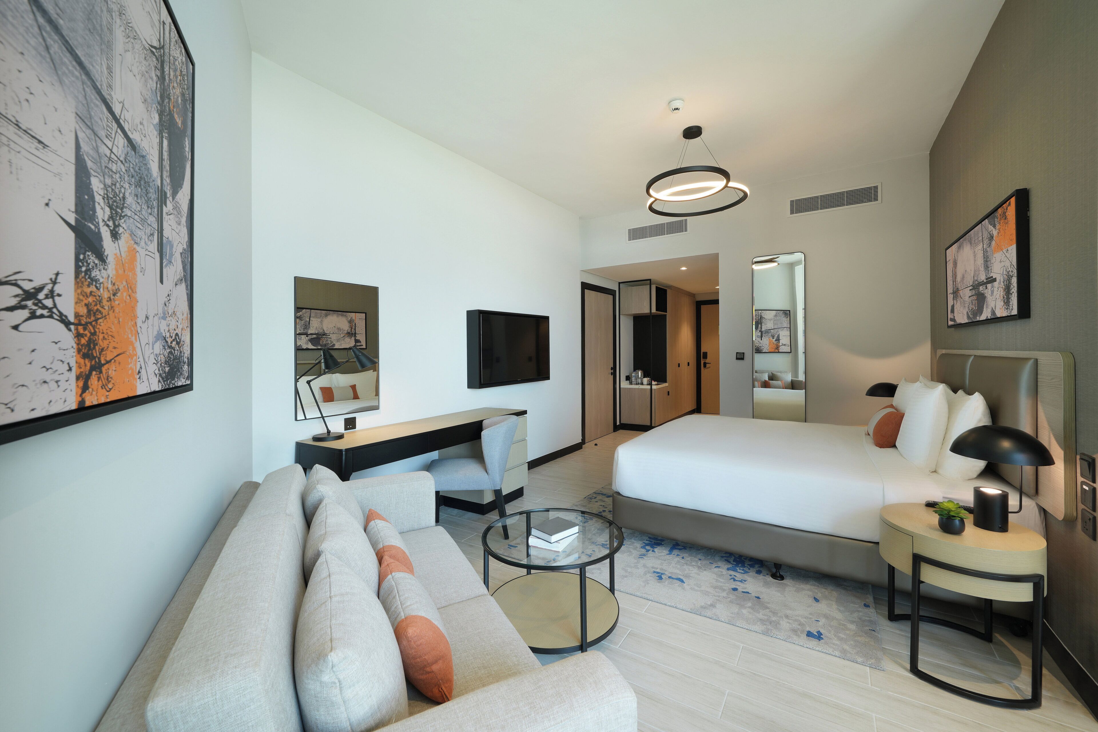 Une chambre d’hôtel moderne équipée d’un lit, d’un canapé, d’un bureau et d’une télévision.