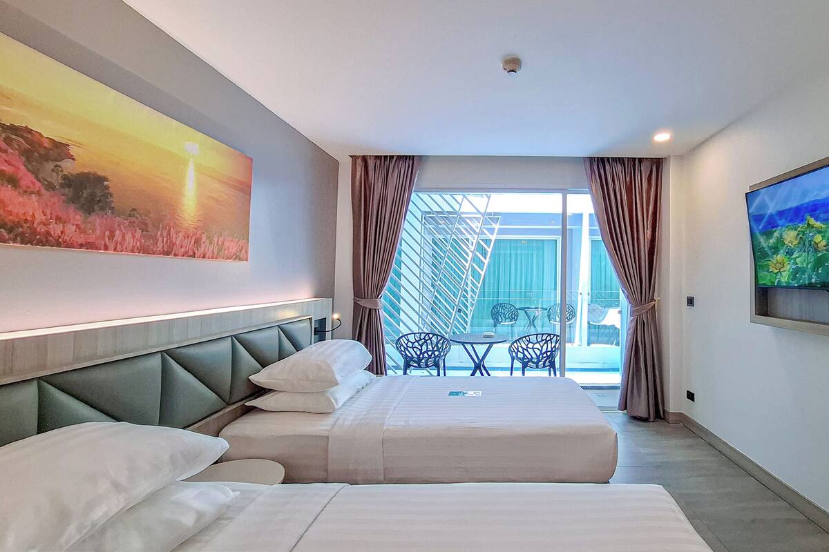 Een hotelkamer met twee bedden, een grote televisie en een balkon met uitzicht.