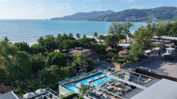 A resort with a rooftop pool, lush greenery, and a view of the sea. - Clarian Hotel Beach Patong (Patong)