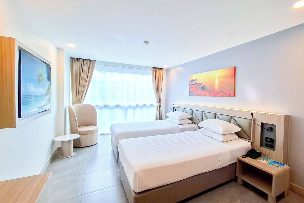 Een hotelkamer met een bed, nachtkastje, stoel en een schilderij aan de muur.