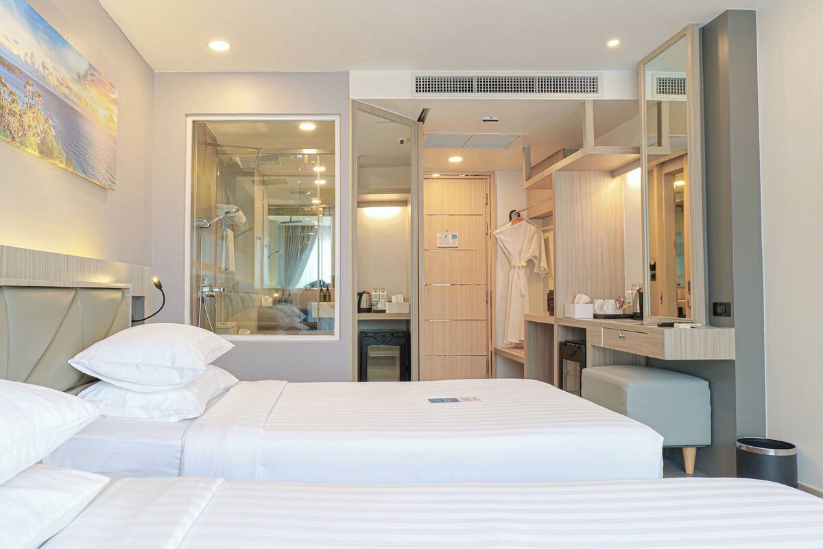 Hotelkamer met een groot bed, een zithoek, een badkamer met douche en een spiegel.