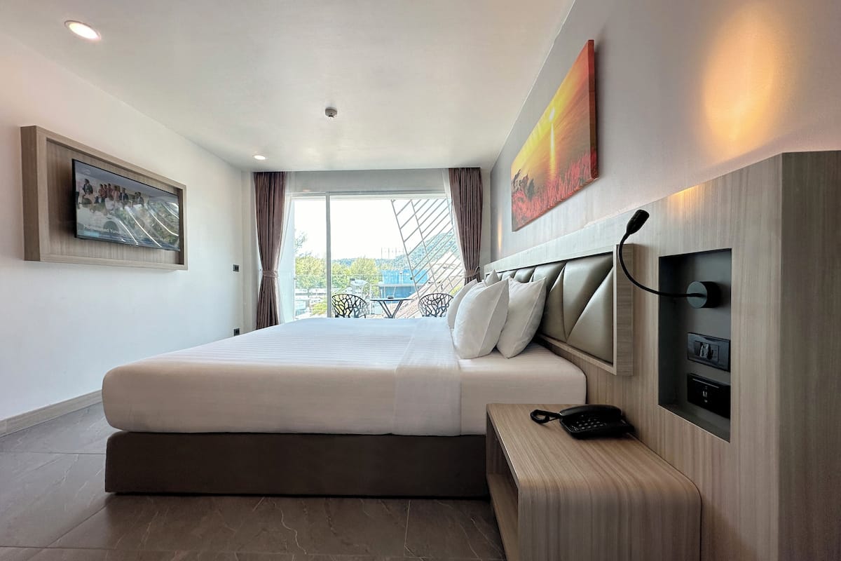 Relax in comfort with a large bed, bedside table, and framed artwork, all set against a scenic outdoor view.
