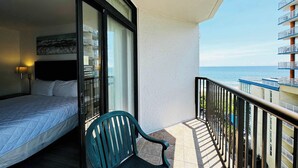 Un balcón con una cama, una silla y vista al mar.