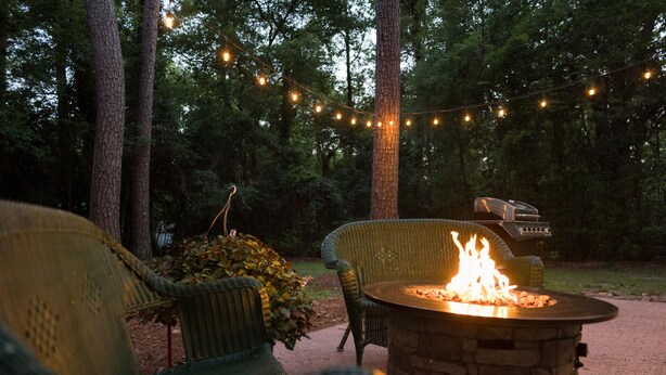 Eine Terrasse mit Korbstühlen, einem Steinkamin und Lichterketten.