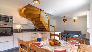 Eine moderne Küche mit einer Holztreppe, einem gedeckten Esstisch und einer Obstschale.