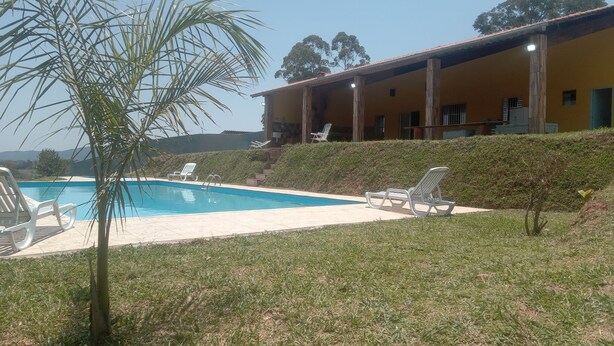 A pool area with lounge chairs and a building with a tiled roof.