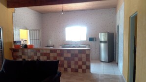 A kitchen with a tiled backsplash, a refrigerator, and a window.
