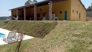 A yellow building with a covered patio area, a swimming pool, and a grassy slope.