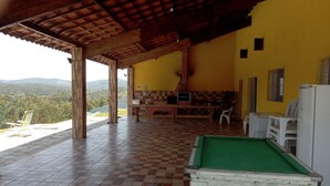 A covered outdoor area with a pool table, a barbecue grill, and a view of the mountains.