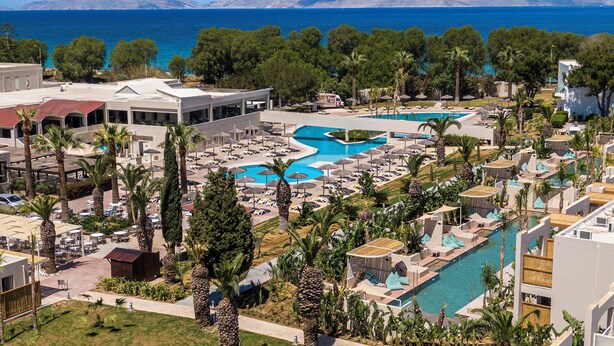A resort with multiple swimming pools, palm trees, and a view of the sea. - Akti Coast Club (Kos)
