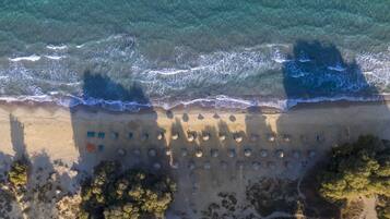 Een privéstrand, wit zand, ligstoelen aan het strand, parasols