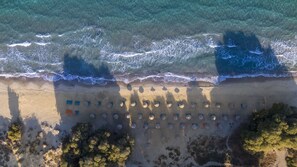 Privat strand, hvit sand, solsenger og parasoller