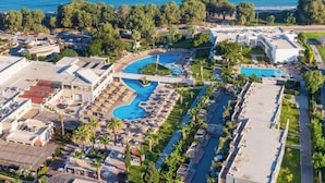 An aerial view of a resort with a large swimming pool, multiple lounge areas, and a beachside location. - Akti Coast Club (Kos)