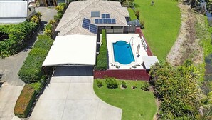 Une maison avec un grand garage, une piscine et des panneaux solaires sur le toit.