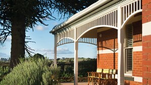 A covered outdoor area with a pergola, brick walls, and a table with chairs.