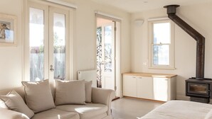 A cozy room with a beige sofa, a wooden cabinet, and a black stove.