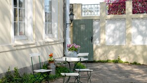 Un patio con una mesa, sillas, una planta en maceta y una puerta verde.