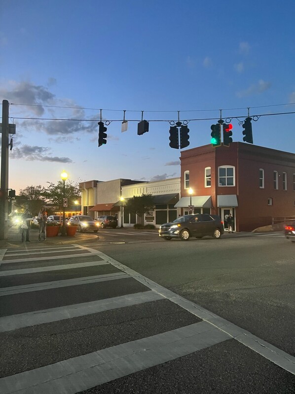 A street intersection with traffic lights, a pedestrian crossing, and buildings in the background. - Historic home in downtown / walking distance to restaurants and local breweries (Milton)
