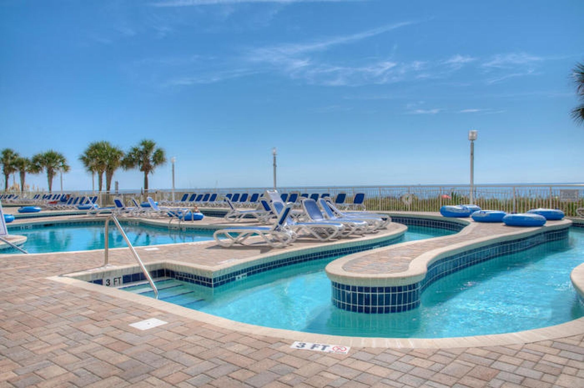 A pool area with lounge chairs and a 3 FT depth marker.