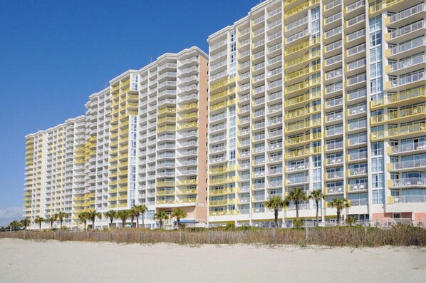 Un hôtel de grande hauteur doté de nombreux balcons, situé près d’une plage.
