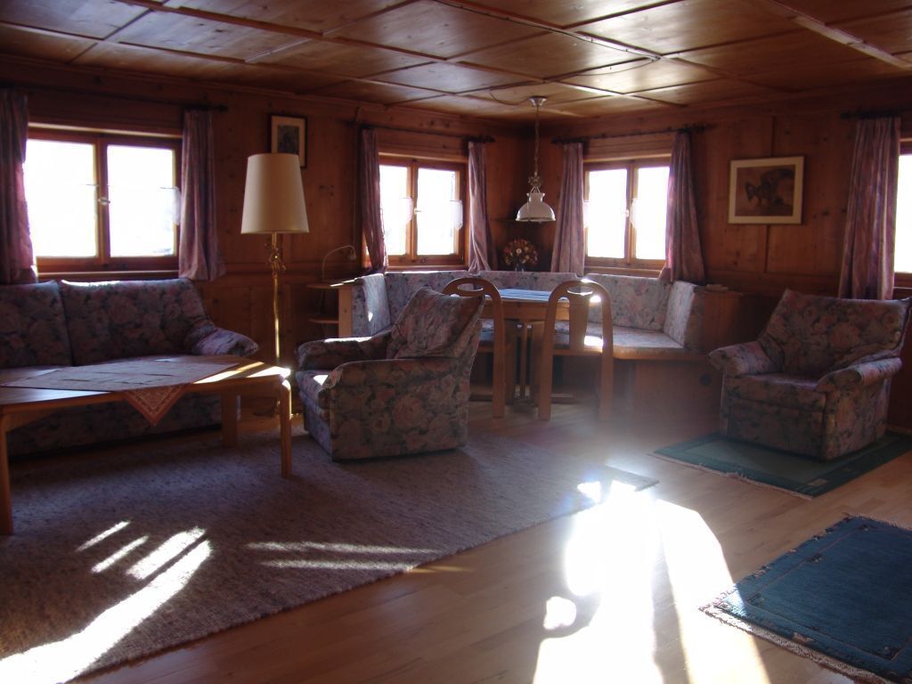 Un interior de cabaña acogedor con techo de madera, un sofá, una mesa y dos sillas.