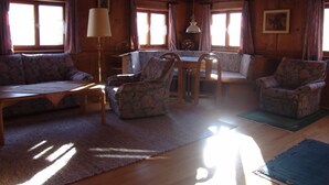 A cozy cabin interior with a wooden ceiling, a sofa, a table, and two chairs. - Vacation apartment 1, Haus Gabi Vacation with pets (Bad Hindelang)