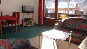 Una sala de estar con sofá, mesa y televisor.