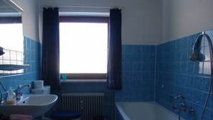 Un baño con bañera, inodoro, lavabo y ventana.
