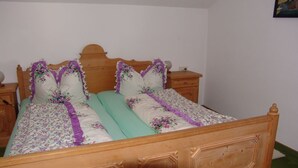 Una cama de madera con ropa de cama floral y dos mesitas de noche.