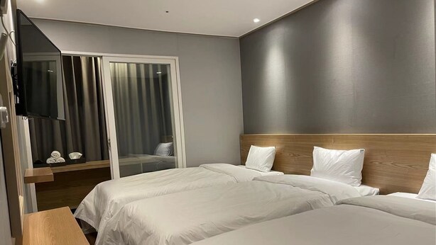 A hotel room with two beds, a TV, and a sliding door leading to a balcony. - The Garden Hotel (Seoul)