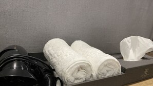 A hotel room drawer containing a pair of white towels, a black headband, and a tissue box. - The Garden Hotel (Seoul)