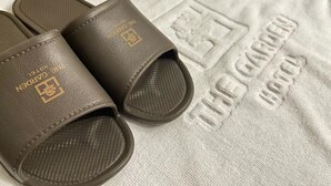 A pair of brown sandals with embossed text on a white towel with similar embossed text. - The Garden Hotel (Seoul)