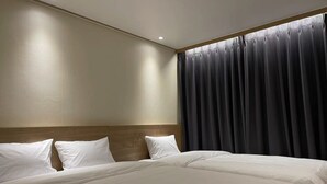 A hotel room with two beds, a wooden headboard, and a large window with dark curtains. - The Garden Hotel (Seoul)