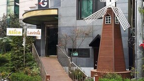 A modern building with a windmill sculpture in front, a sign for 'Alice Lavinia', and a 'G' logo above the entrance. - The Garden Hotel (Seoul)