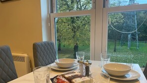 Une table à manger avec des assiettes, des bols et des verres blancs, un paquet de collations et un salier.