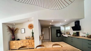 Una cocina moderna con una isla central, muebles de madera y un comedor con una mesa grande y sillas.